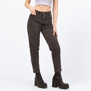 May include: Dark gray high-waisted jeans with a classic five-pocket design. The jeans have a straight leg cut and are paired with black platform boots. The denim appears to be stonewashed for a vintage look.