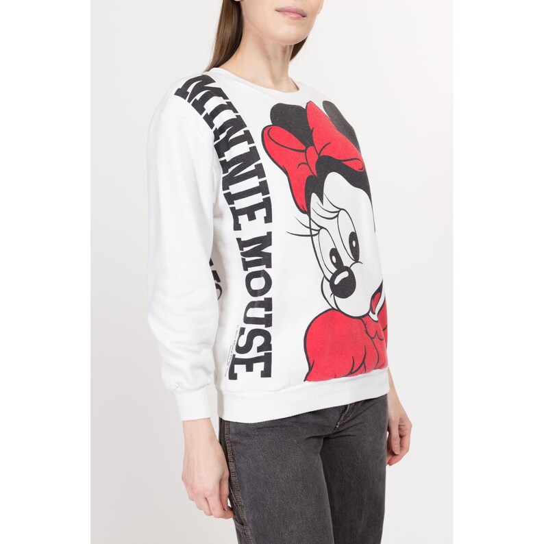 May include: White sweatshirt with a black and red Minnie Mouse graphic and the text "Minnie Mouse" printed vertically on the side.
