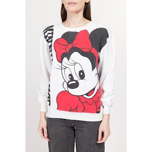 May include: White sweatshirt with a black and white striped design on the left side and a large graphic of Minnie Mouse on the right side. Minnie Mouse is wearing a red bow and a red dress.