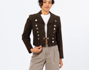 May include: A brown suede jacket with silver button accents. The jacket has a cropped length and a collar.
