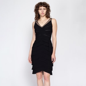 May include: A black sleeveless dress with a layered skirt and a sheer mesh panel at the neckline.
