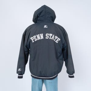Puede incluir: Chaqueta con capucha azul marino con el texto "PENN STATE" en letras blancas en la espalda. La chaqueta tiene un logotipo de Starter en la capucha y los puños. Los puños y el dobladillo tienen rayas blancas y azul marino.