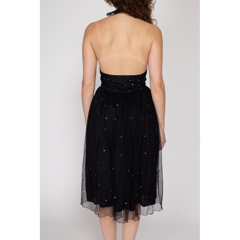 May include: A black tulle dress with a halter neckline and green sequins. The dress has a fitted bodice and a flowing skirt.