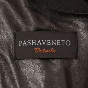 May include: Close-up of a black leather jacket with a label that reads "PASHAVENETO Details" in white and orange lettering. The jacket's leather has a textured appearance.