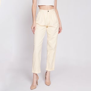 Peut inclure: Un pantalon taille haute de couleur jaune clair avec des plis à l'avant. Le pantalon a une jambe droite et est retroussé en bas.