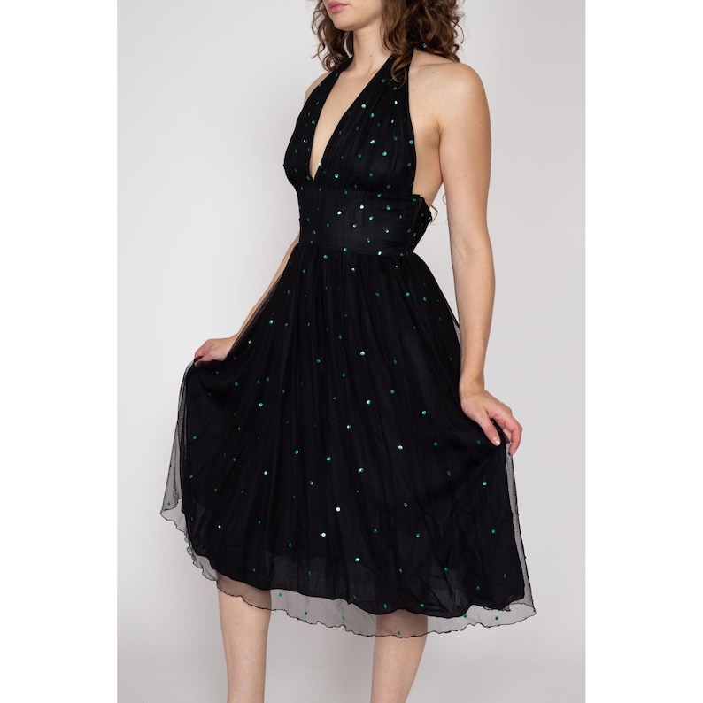May include: A black tulle dress with a halter neckline and green polka dots. The dress has a fitted bodice and a full skirt.