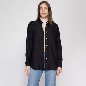 May include: A black long-sleeved shirt with a mock neck and button closure. The shirt has a relaxed fit and is made of a soft, lightweight fabric.