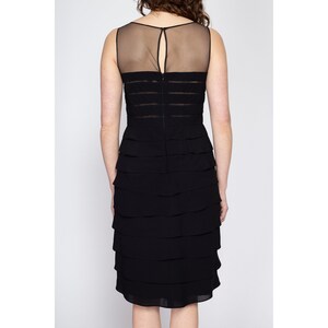 May include: A black sleeveless dress with a sheer mesh panel at the bodice and a tiered skirt.