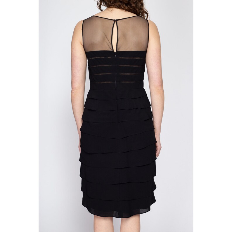 May include: A black sleeveless dress with a sheer mesh panel at the bodice and a tiered skirt.