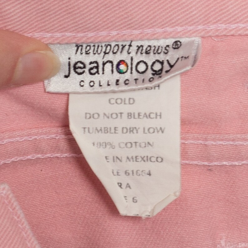 Może przedstawiać: Biała metka pielęgnacyjna z tekstem "newport news jeanology COLLECTION" i instrukcjami pielęgnacyjnymi: "COLD, DO NOT BLEACH, TUMBLE DRY LOW, 100% COTON, E IN MEXICO, LE 61664, RA 6".
