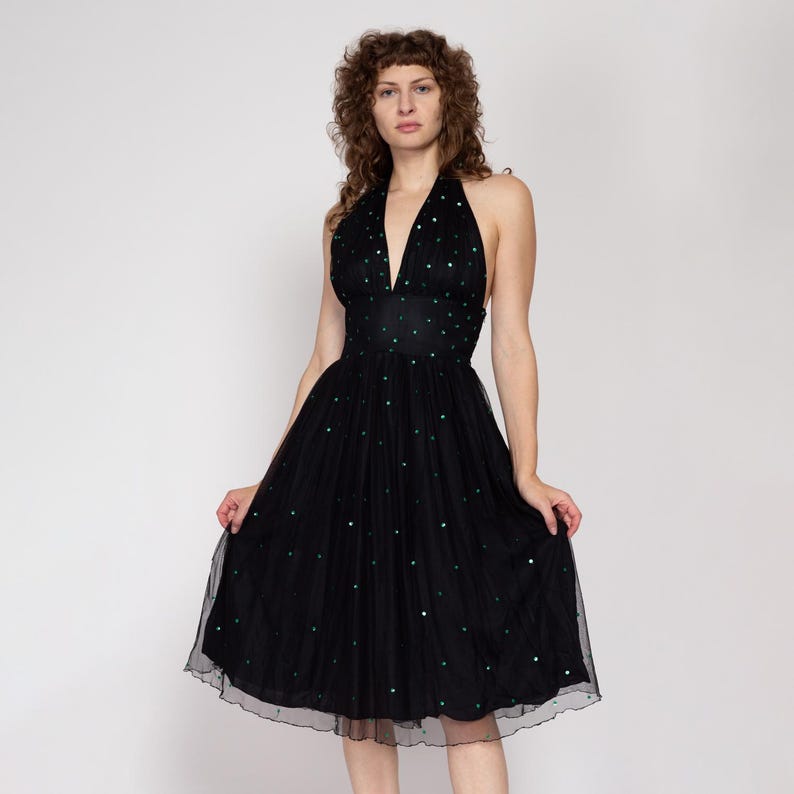 May include: A black halter dress with a fitted bodice and a full skirt. The dress is adorned with small green sequins.