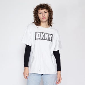 May include: White t-shirt with a black and white DKNY logo printed on the front.