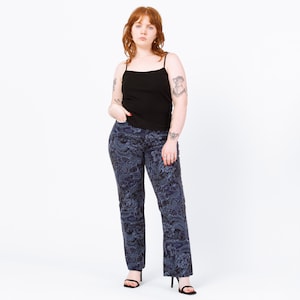 Peut inclure: Une personne porte un débardeur noir et un pantalon bleu foncé à imprimé floral. Le pantalon a une coupe droite et est associé à des sandales à talons noires. Le fond est blanc uni.
