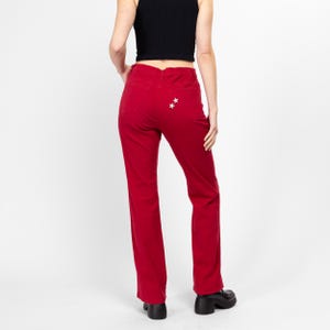 Puede incluir: Pantalón de pana rojo acampanado con dos estrellas plateadas en los bolsillos traseros.