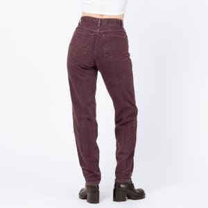 May include: A pair of high-waisted, dark burgundy jeans. The jeans have a classic five-pocket design and a straight leg fit. The model is wearing black heeled boots. The background is plain white.