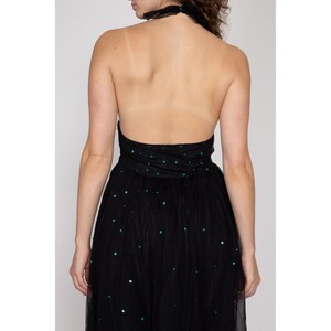 May include: A black tulle dress with green sequins. The dress has a halter neckline and a fitted bodice. The skirt is full and flowing.