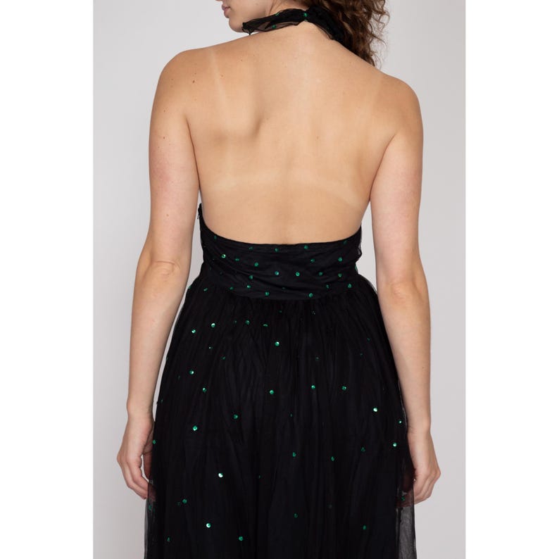 May include: A black tulle dress with green sequins. The dress has a halter neckline and a fitted bodice. The skirt is full and flowing.