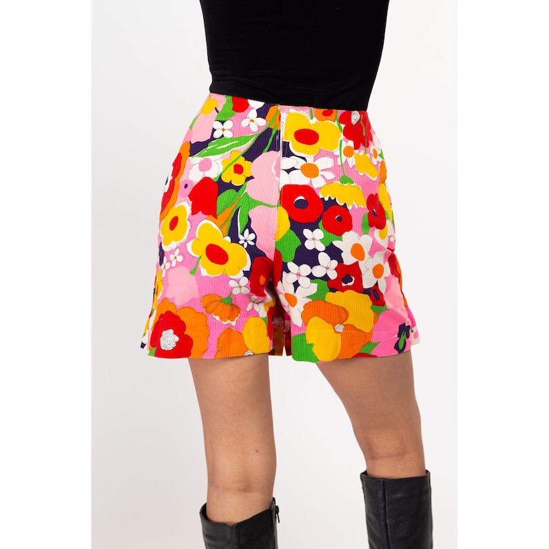 May include: A pair of pink, orange, yellow, red, and green floral print shorts. The shorts have a high waist and a wide leg.