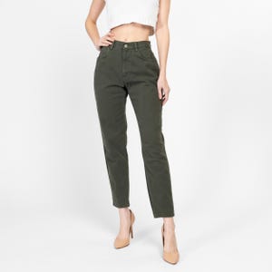 Puede incluir: Un par de pantalones vaqueros de tiro alto y pierna recta en color verde oliva oscuro. Los vaqueros tienen un diseño clásico de cinco bolsillos y cierre de botón.