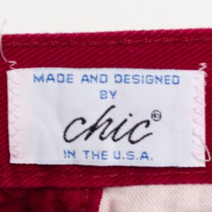 May include: A white label with blue text that reads "Made and Designed by Chic&reg; in the U.S.A." The label is sewn onto a burgundy fabric.