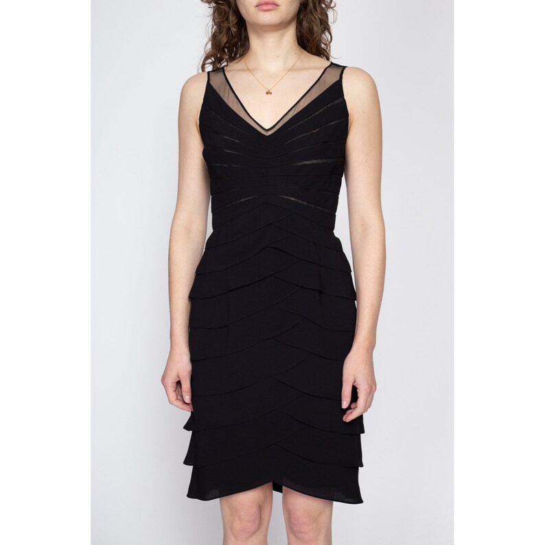 May include: A black sleeveless dress with a layered skirt and a sheer neckline.