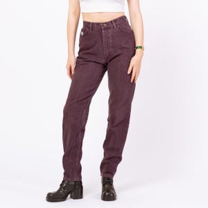 May include: Dark purple denim jeans with a classic five-pocket design. The jeans have a high waist and a straight leg fit. The model is wearing black boots. The jeans are made of a durable denim material.
