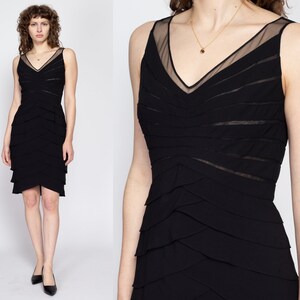 May include: A black sleeveless dress with a layered skirt and a sheer mesh panel at the neckline.