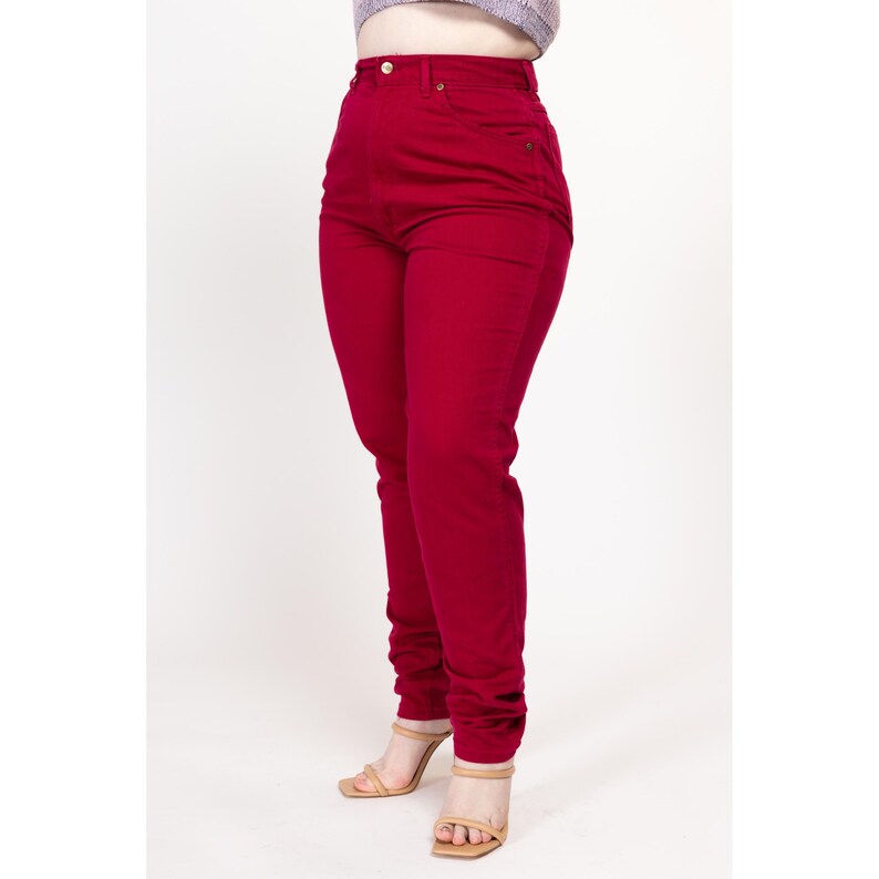 May include: A pair of high-waisted, red jeans. The jeans are a slim fit and have a straight leg.