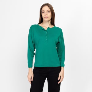 May include: A long-sleeved, green shirt with a button-up neckline. The shirt has a relaxed fit and is made of a soft, comfortable fabric.