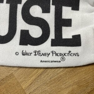 May include: White t-shirt with the word "MOUSE" printed in black. The shirt has a copyright notice for Walt Disney Productions and the Americanwear logo.