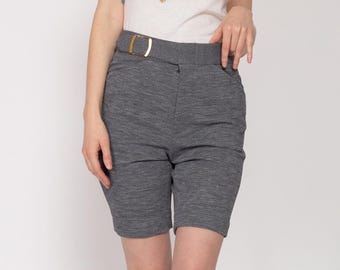 Könnte beinhalten: Graue, hochgeschnittene Shorts mit einer goldenen Gürtelschnalle. Die Shorts sind aus einem strukturierten Stoff.