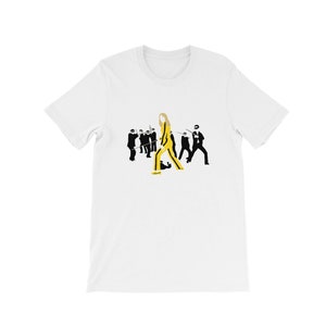 Könnte beinhalten: Weißes T-Shirt mit einer schwarzen und gelben Grafik einer Frau in einem gelben Overall, die an einer Gruppe von Männern in schwarzen Anzügen vorbeigeht.