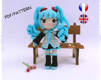 May include: Crochet pattern PDF for a blue haired anime character doll. The doll is sitting on a wooden bench. The pattern is available in French and English.