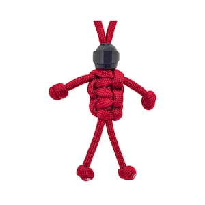 May include: A red paracord figure with a black plastic head. The figure has arms and legs that are tied in knots.