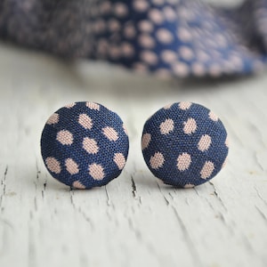 Könnte beinhalten: Ein Paar Ohrringe aus Stoff mit blauen und rosa Punkten. Die Ohrringe sind rund und haben eine Knopfform.