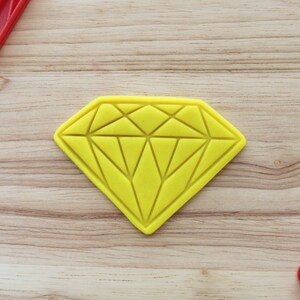 May include: A yellow diamond-shaped cookie cutter on a wooden surface.