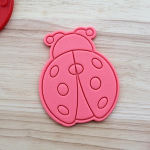 May include: Pink ladybug cookie cutter with a detailed design. The cutter has a raised edge and a smooth surface.
