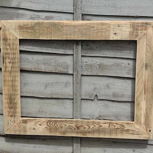 May include: A rustic wooden picture frame with a natural wood finish. The frame is made from reclaimed wood and has a simple, rectangular shape.