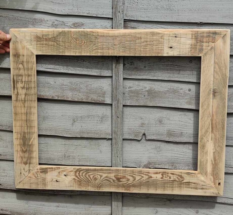 May include: A rustic wooden picture frame with a natural wood finish. The frame is made from reclaimed wood and has a simple, rectangular shape.