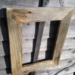 May include: A rustic wooden picture frame with a weathered gray and brown finish. The frame is made of reclaimed wood and has a simple, rectangular design.