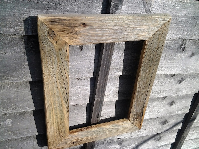 May include: A rustic wooden picture frame with a weathered gray and brown finish. The frame is made of reclaimed wood and has a simple, rectangular design.