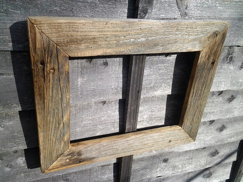 May include: A rustic wooden picture frame with a weathered, natural finish. The frame is made of reclaimed wood and has a rectangular shape.