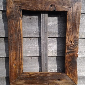 May include: A rectangular wooden picture frame with a dark brown finish. The frame has a rustic, weathered appearance with visible wood grain and knots. The frame is empty, ready for a photo or artwork.