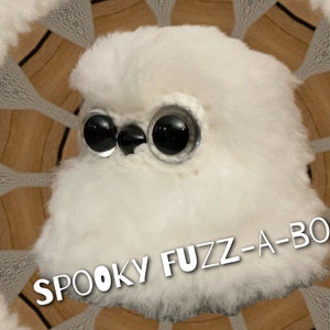 May include: A white fluffy toy with large black eyes and the text "SPOOKY FUZZ-A-BOO!" on a brown background.