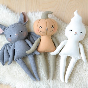 Peut inclure: Trois jouets en peluche d'Halloween faits à la main : une chauve-souris grise, une citrouille beige et un fantôme blanc. Chaque jouet a un visage amical avec des détails brodés.