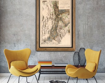May include: A framed vintage map of the Yellowstone region, with detailed topography and rivers, hangs on a gray wall above a coffee table with two yellow armchairs.