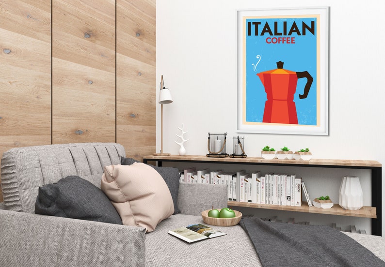 Może przedstawiać: Wnętrze salonu z szarą sofą, drewnianą p&oacute;łką z książkami i oprawionym plakatem z napisem "ITALIAN COFFEE" z czerwoną i czarną ilustracją dzbanka do kawy.