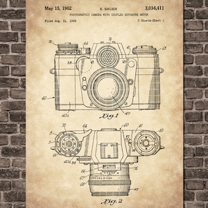 May include: A black and white line drawing of a photographic camera with coupled exposure meter. The drawing is from a patent filed on August 21, 1959, and granted on May 15, 1962. The patent number is 3,034,411. The drawing shows two views of the camera, one from the top and one from the side. The drawing is labeled "Fig. 1" and "Fig. 2".