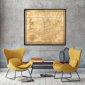 May include: A vintage map of Cincinnati, Ohio from 1849, printed on aged paper and framed in black. The map shows the city's streets, rivers, and landmarks.