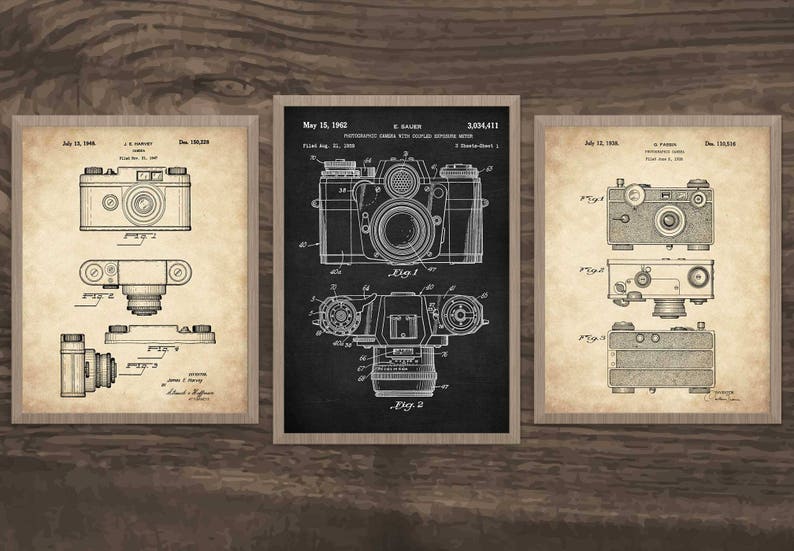 Op de afbeelding: Drie vintage patenttekeningen van camera's. De eerste tekening toont een camera met een enkele lens, de tweede tekening toont een camera met een dubbele lens en de derde tekening toont een camera met een enkele lens. Alle drie tekeningen zijn in zwart-wit en hebben een vintage esthetiek.